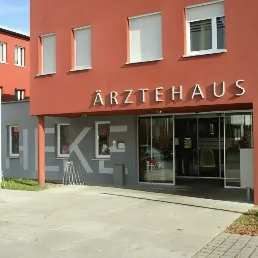 Eingang des Ärztehauses Weiden mit roter Fassade und gläserner Schiebetür